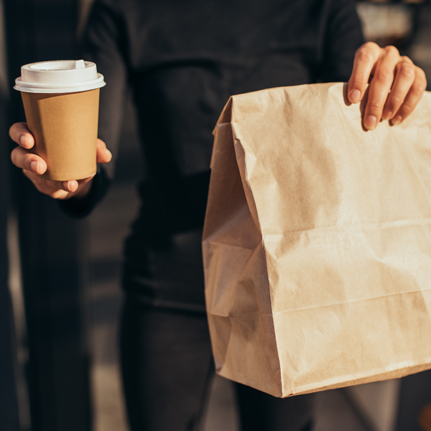 A person holding a cup and a paper bag
